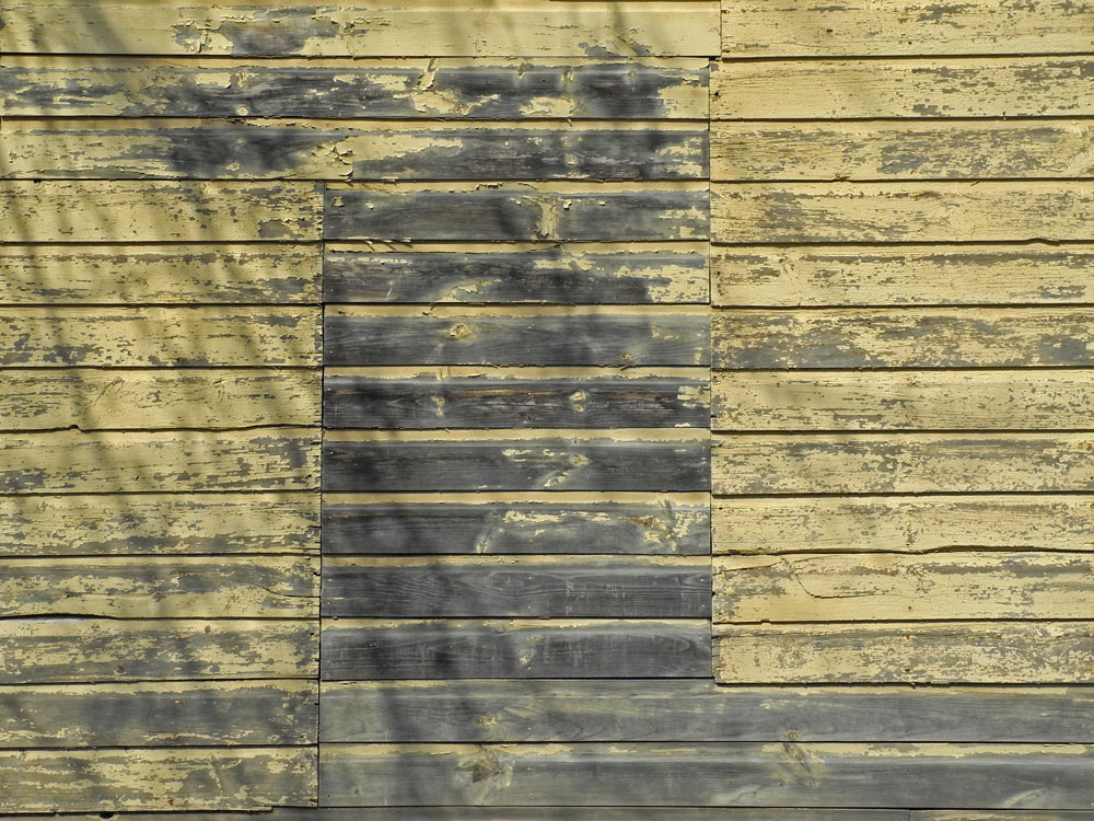 Side of yellow wooden building on Goodman Street in Rochester, New York