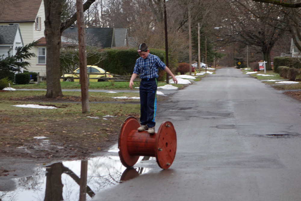 Kid on utility company spool, Rochester, New York