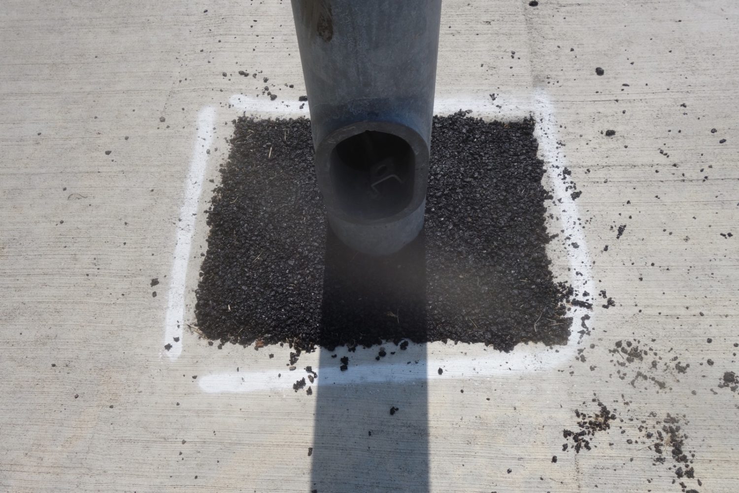 Light pole, pavement, concrete, spray paint and shadow on Mount Hope Avenue