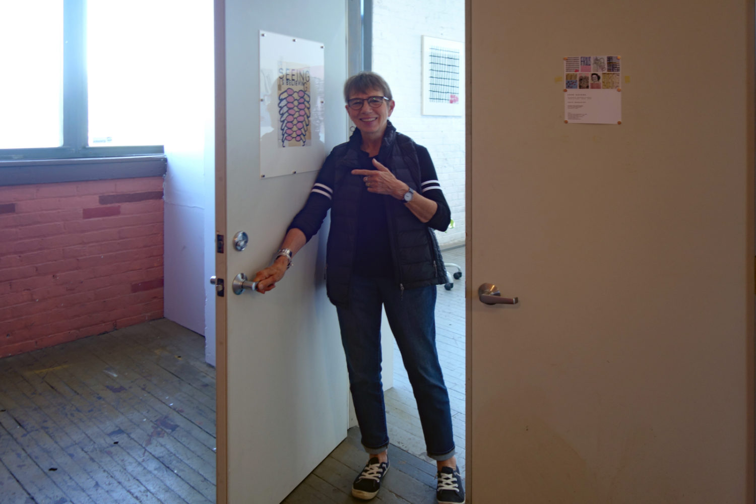 Anne Havens in doorway of Colleen Buzzard's Studio with her "Seeing Is Believing" piece on the door.