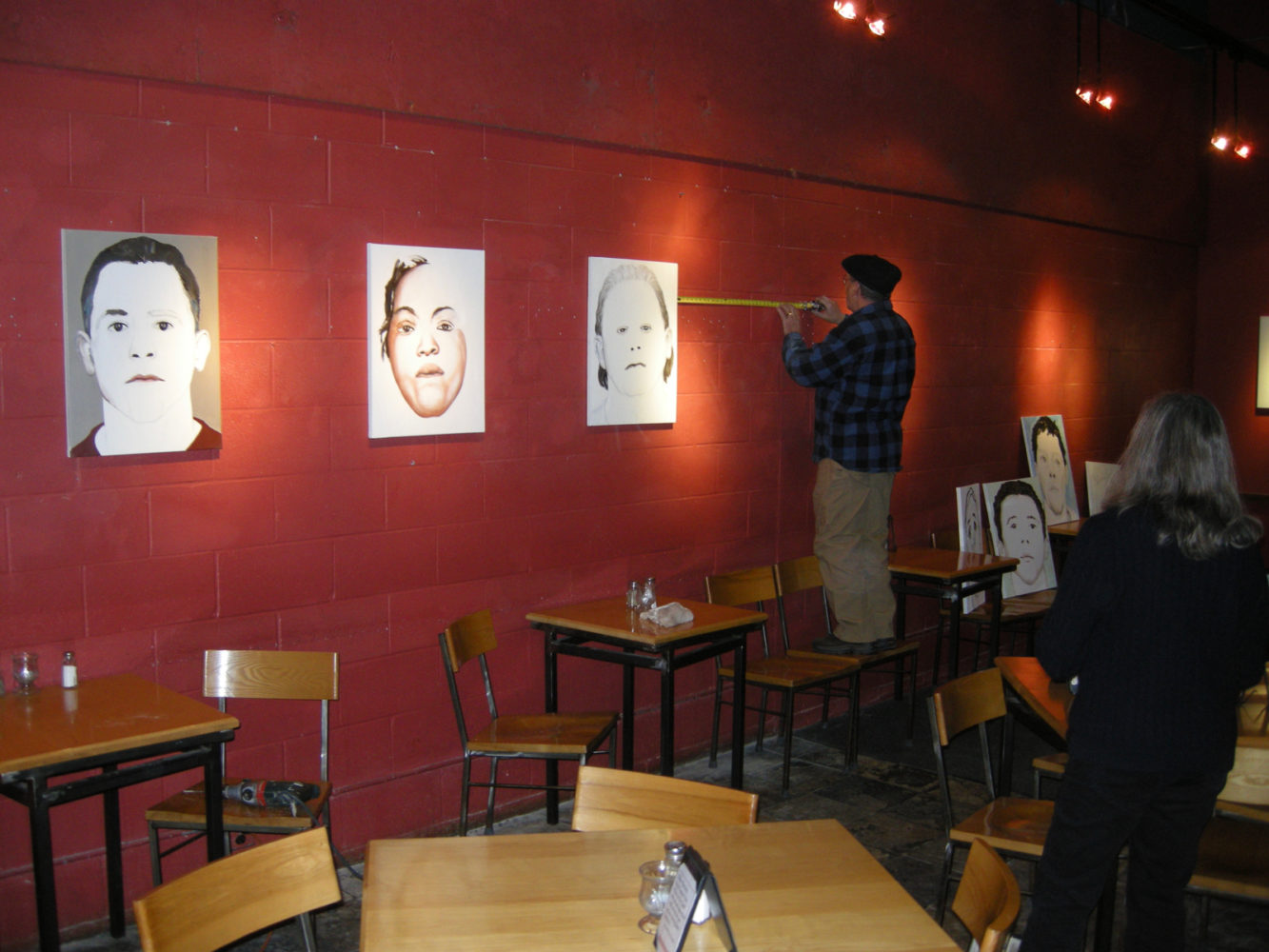 Peter Monacelli installing Paul Dodd "Local Crime Faces 2009" at Little Theatre Café 2009