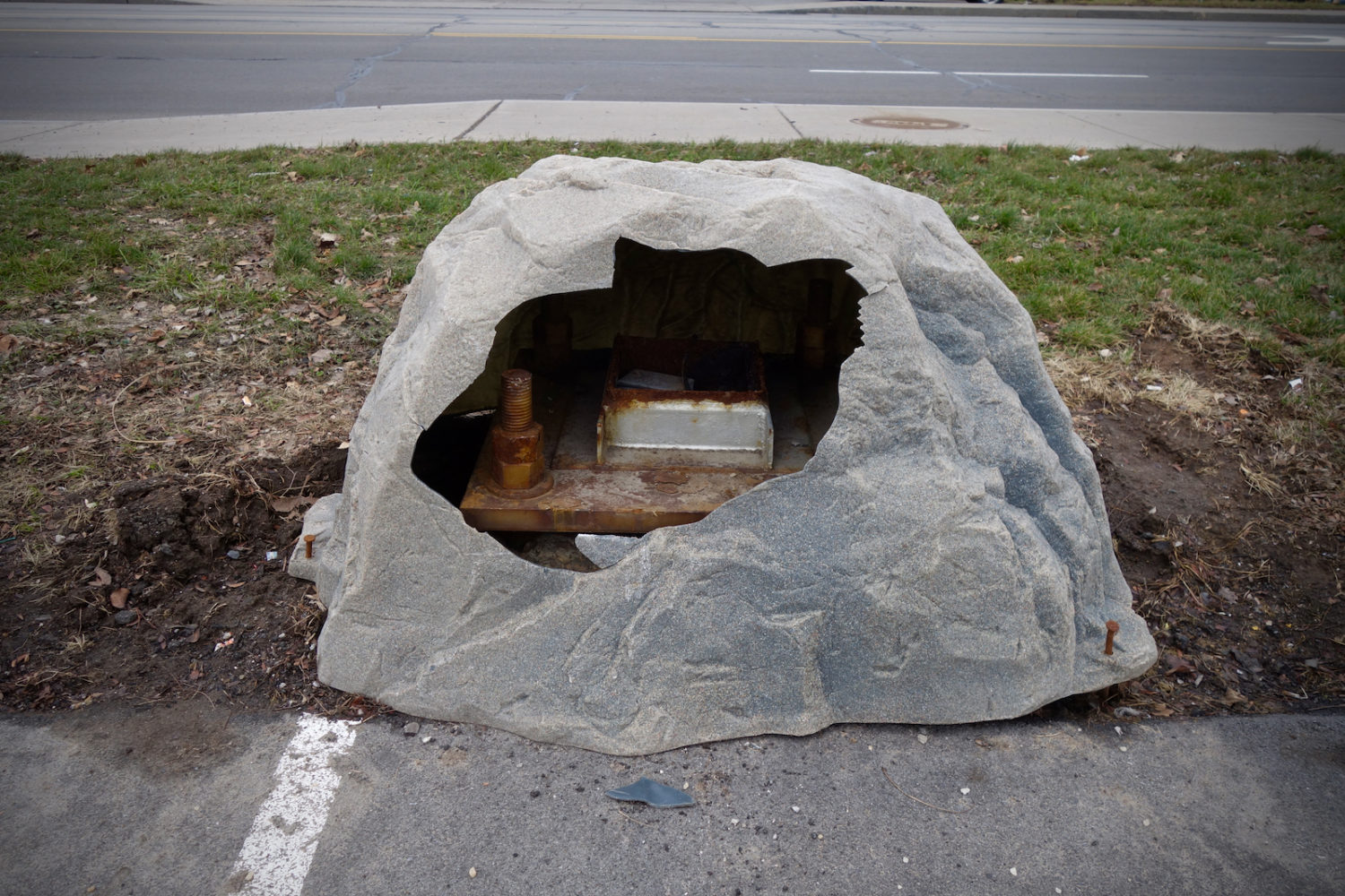 One of the local wonders of the world, this broken, fake rock, hiding some mysterious machinery, formerly nailed to a surface and now sitting in a parking lot near Starbucks on East Ridge Road.