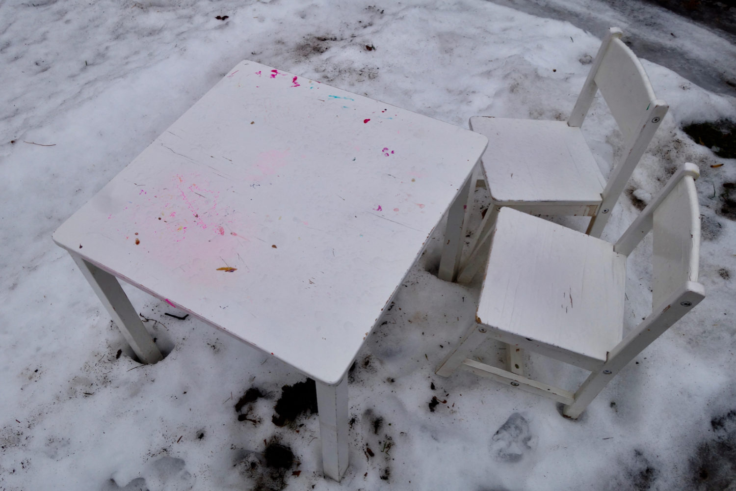 Small white table and chairs by the street in the snow