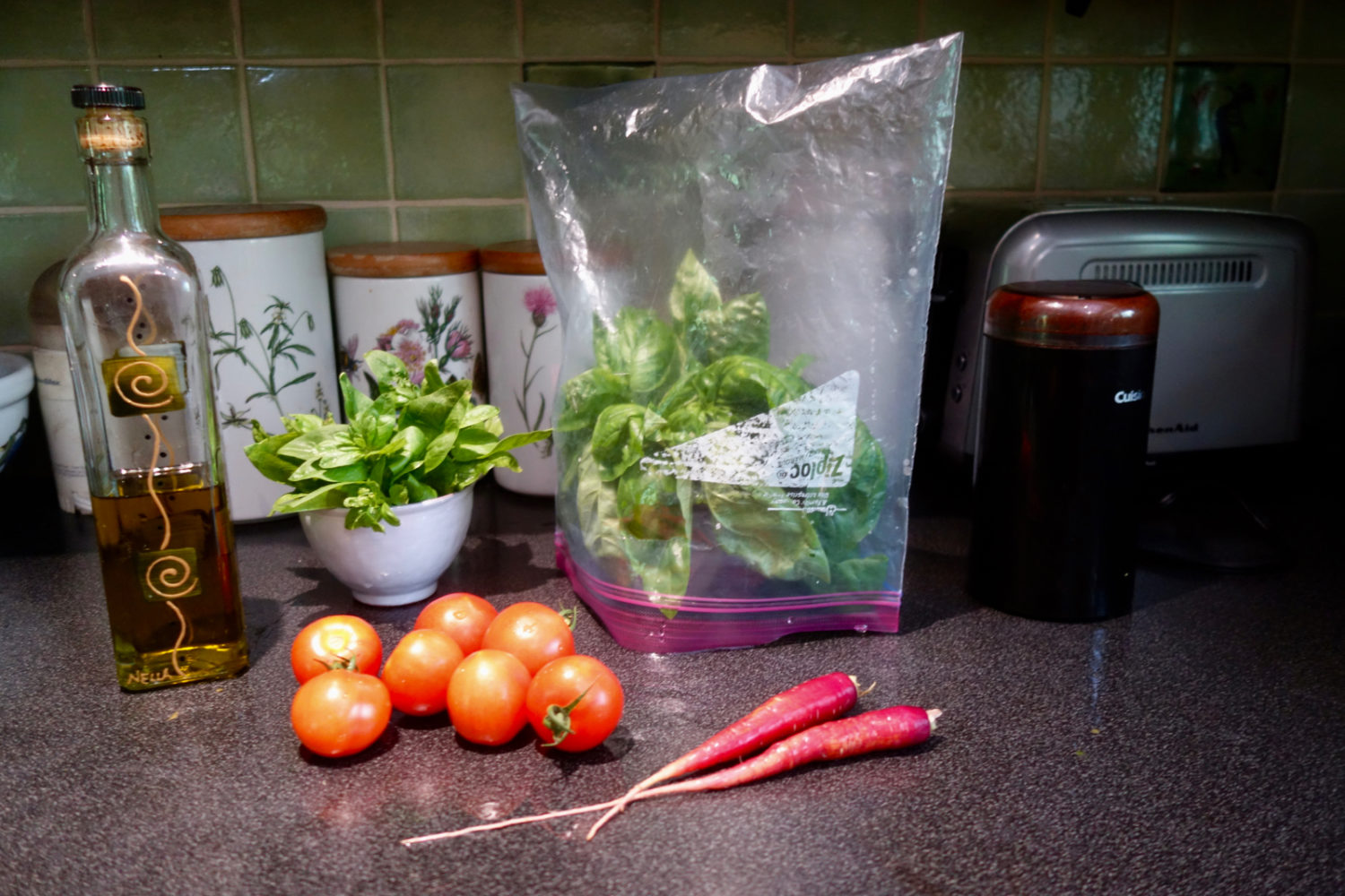 Olive oil, basil, basil in a plastic bag tent and carrots from the garden