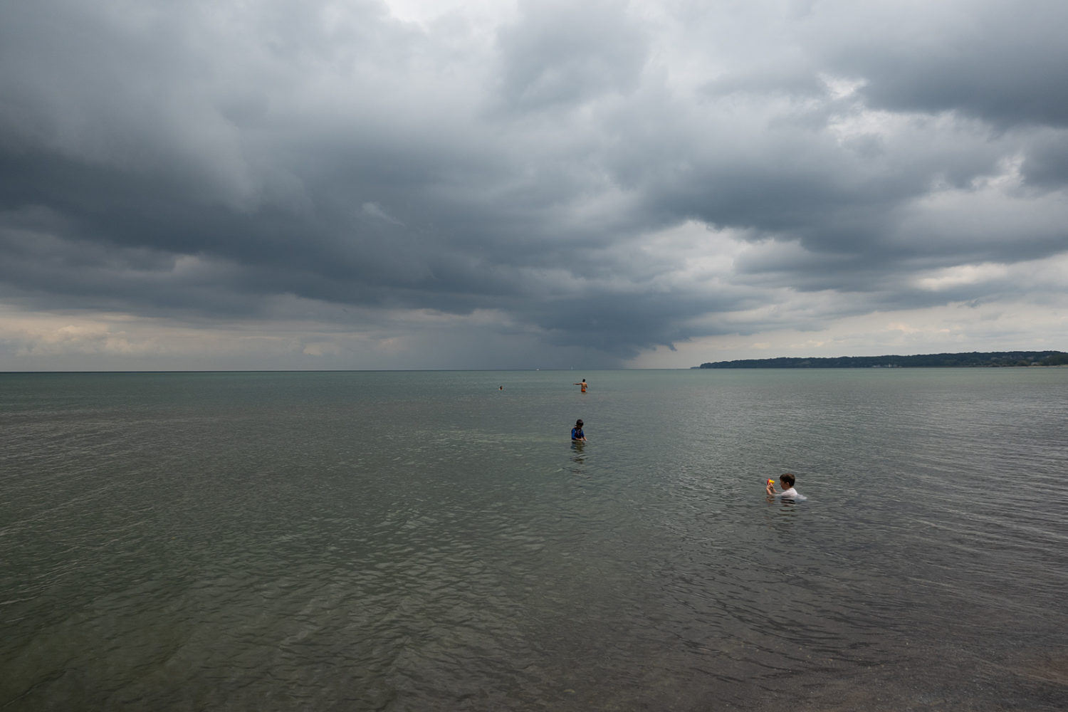 Bathers in Lake Ontario with dark clouds