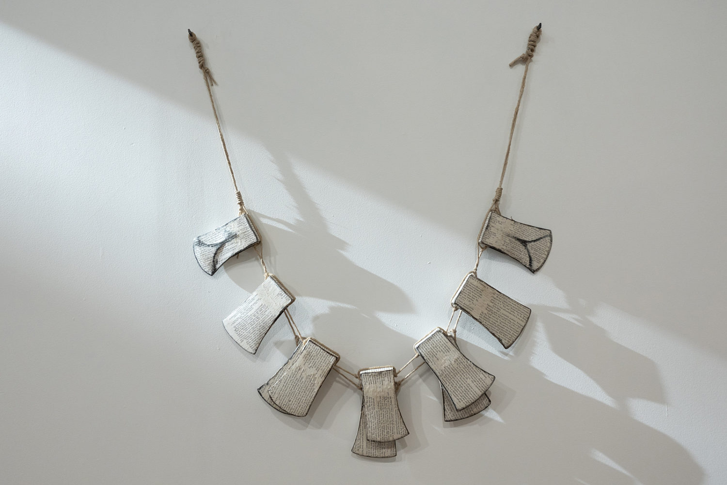Stephana McClure's axe head necklace as wall hanging at Bienvenu Steinberg & Partner