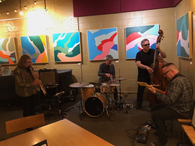 Jim Thomas photo of Margaret Explosion playing at Little Theatre Café with Jim Thomas paintings on the wall
