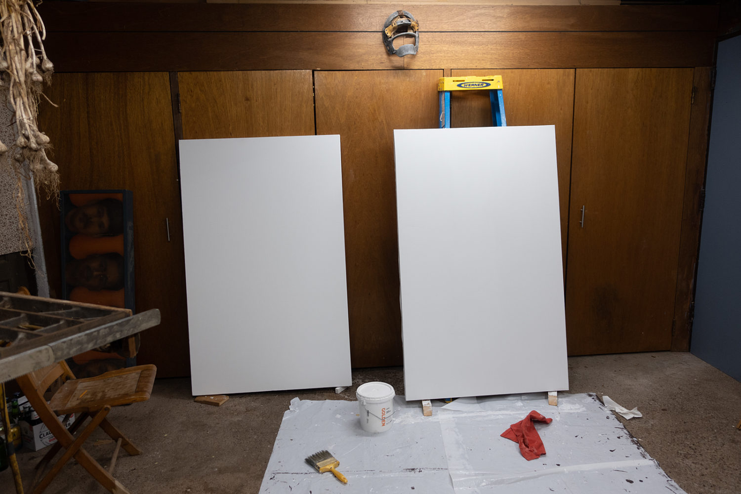 Two freshly primed canvases in garage with garlic
