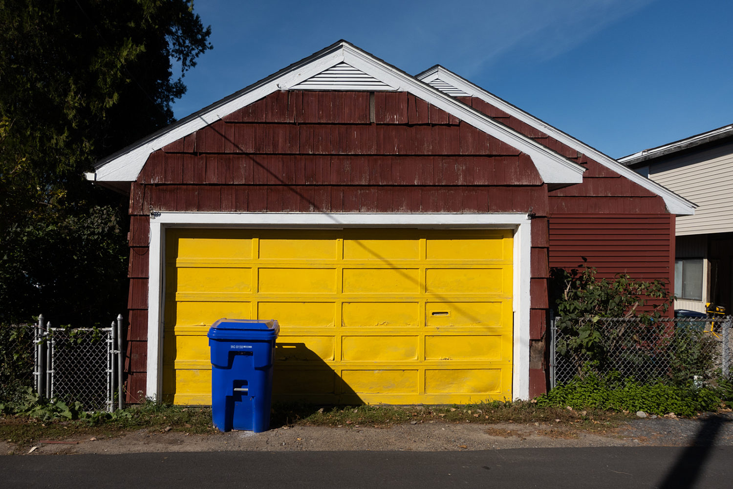 Red garage with yellow door and blue trash can in Olcott, New York