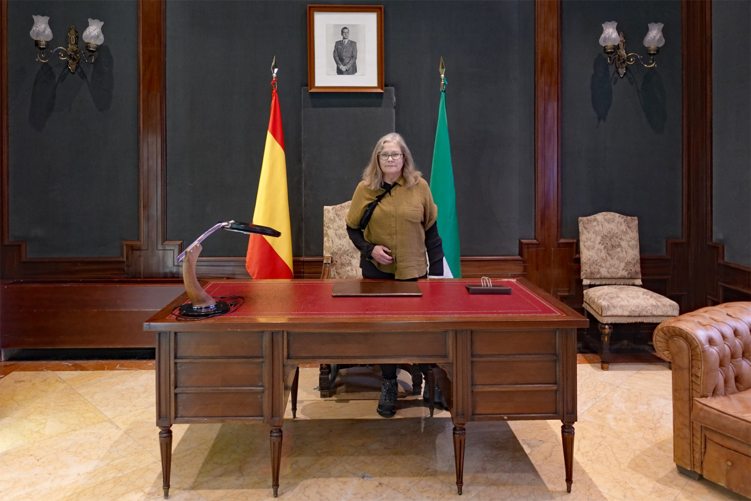 Peggi with picture of Juan Carlos behind desk in Diputacion de Sevilla building