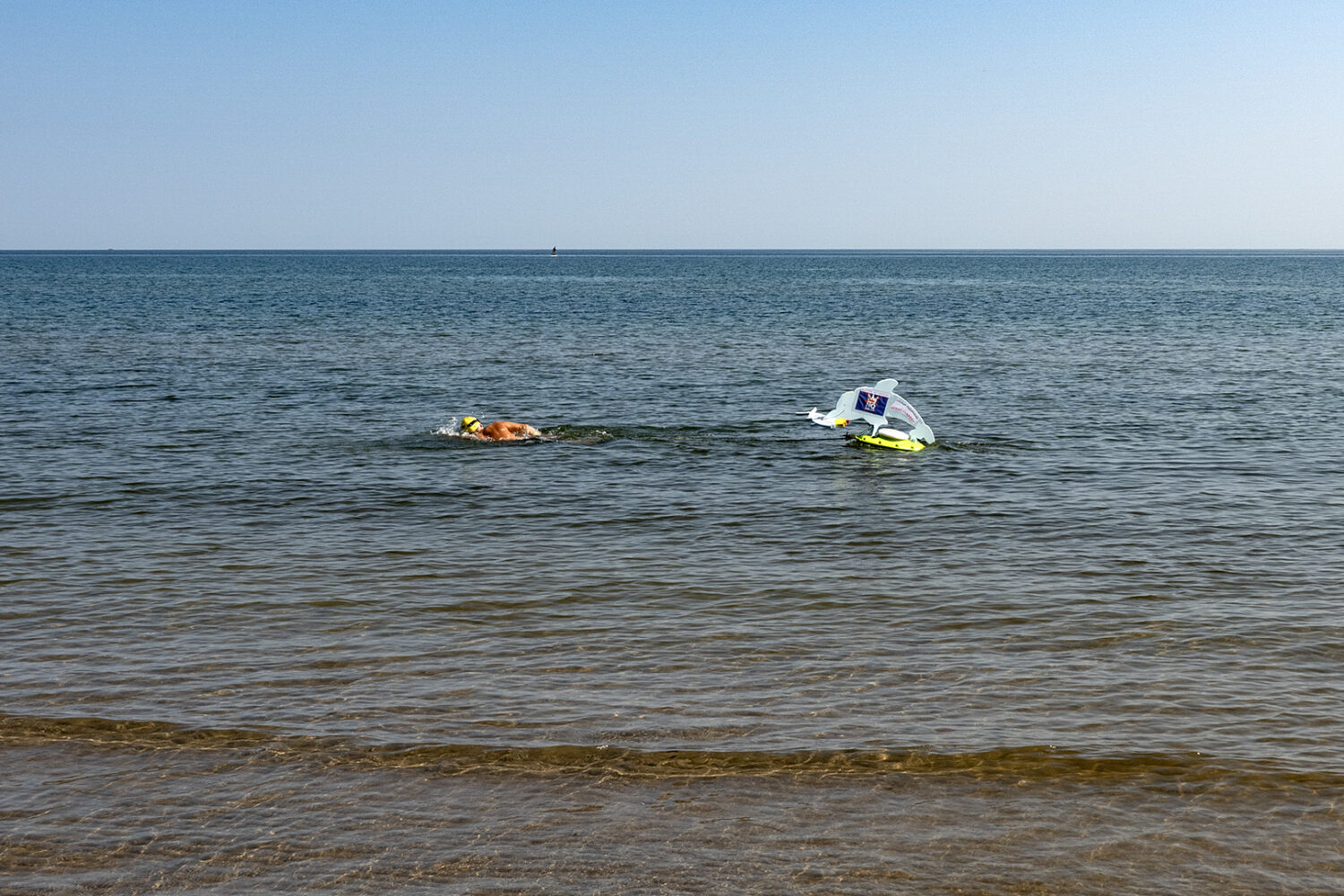 Swimmer pulling a "No Kings" protest sign at Durand Eastman Beach